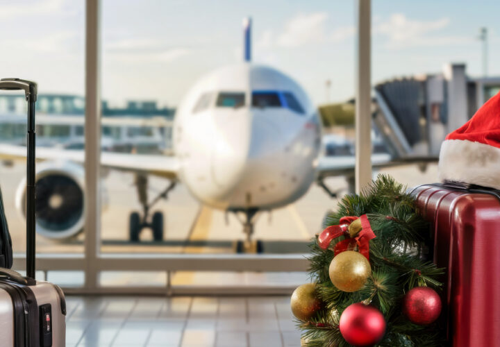 Suitcases with Santa hat on top in airport with aeroplane in background