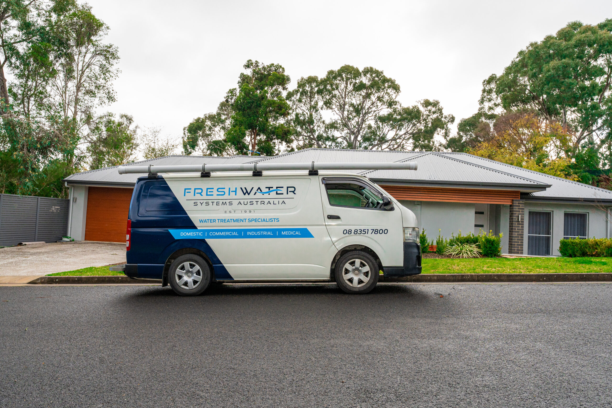 A Freshwater Systems domestic service van parked outside a modern home